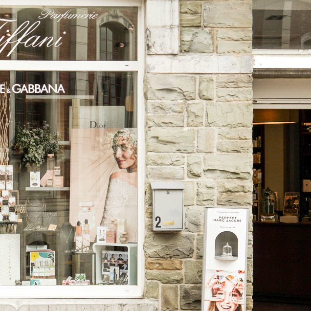 Façade de la parfumerie Tiffani à Herve, avec une vitrine mettant en avant des bijoux et des parfums de marques comme Dolce & Gabbana et Dior.
