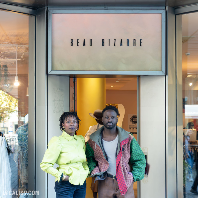 Sur cette photo, les 2 gérants posent devant l'entrée de Beau Bizarre, une friperie moderne située à Liège, avec une devanture élégante et un intérieur stylé en arrière-plan.