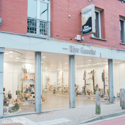 Façade du magasin "Rive Gauche", spécialisé dans la vente de chaussures et d’accessoires. La devanture en briques rouges et grandes vitrines offrent une vue sur l’intérieur, mettant en avant une sélection de sacs et de chaussures élégantes.