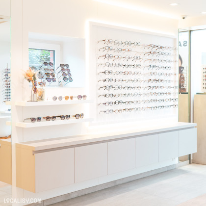 Vue d’un présentoir dans un magasin d’optique, mettant en avant une collection de lunettes de soleil et de vue. L’espace est lumineux, moderne et organisé, avec un design épuré.