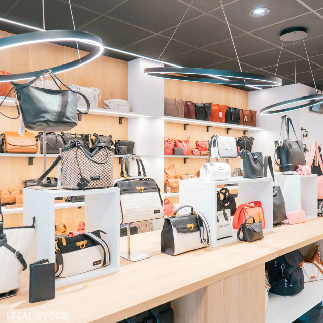 Intérieur du magasin Peau d’âne à Spa, spécialisé en maroquinerie et bagagerie, présentant des sacs colorés Longchamp.