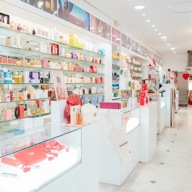 Vue d’ensemble lumineuse du magasin de parfum Audrey à Fléron, avec des comptoirs blancs et des produits de beauté soigneusement exposés.