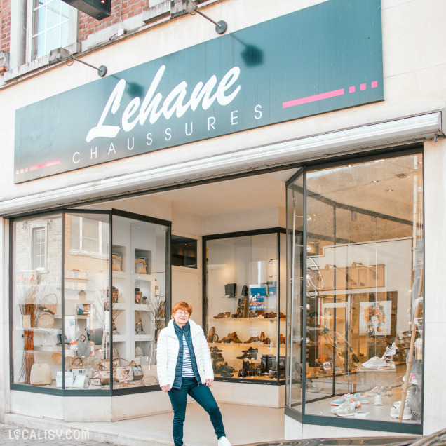 Façade du magasin "Lehane Chaussures" avec une grande vitrine transparente ; une femme pose devant l'entrée.