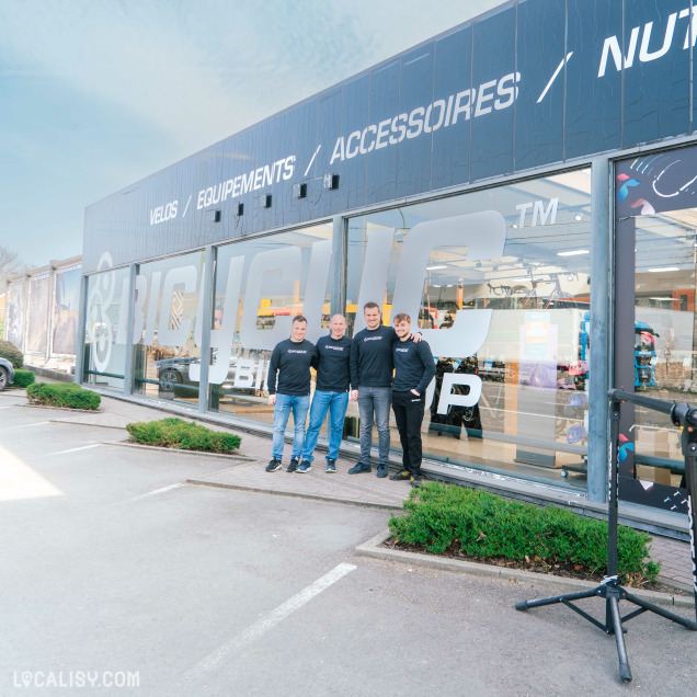 Équipe du magasin Bicyclic à Marche-en-Famenne posant devant la vitrine du commerce de vélos.