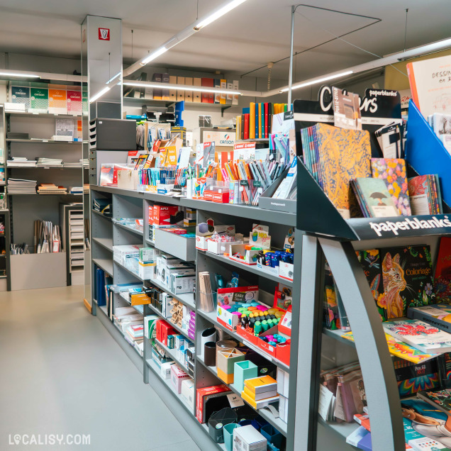 Rayon de sacs à dos dans un magasin, avec une large sélection de modèles colorés et de marques comme Eastpak, accrochés au mur et disposés en plusieurs rangées.