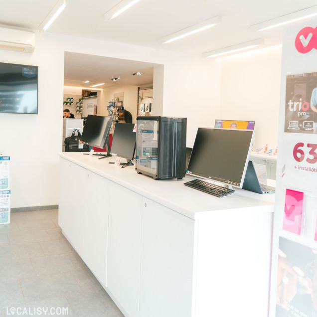 Vue latérale du comptoir d'exposition montrant des écrans d'ordinateur, une tour PC et des accessoires dans un magasin informatique.
