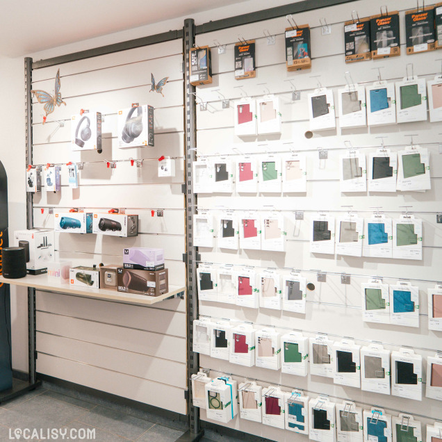 Mur d’accessoires high-tech comprenant des coques de téléphone, enceintes JBL et produits de protection, exposés de façon organisée.