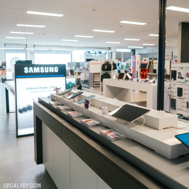 Espace Samsung du magasin présentant des smartphones et tablettes Galaxy, avec signalétique lumineuse et produits en libre accès sur un comptoir design.