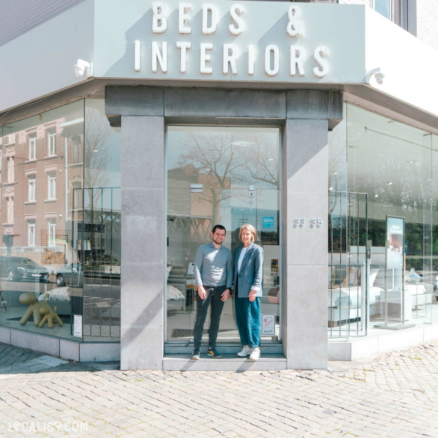 Façade du magasin de literie Beds & Interiors à Liège avec deux responsables devant l’entrée.