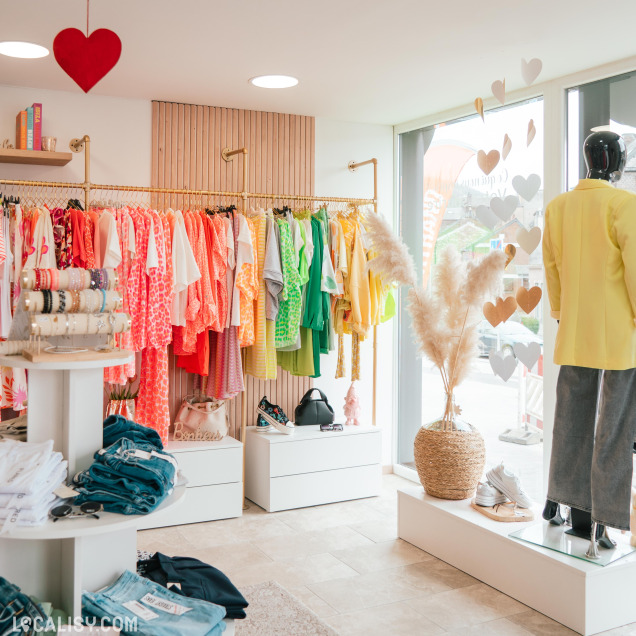 Présentation de vêtements colorés et accessoires dans le magasin G’rien à Mettre à Huy.