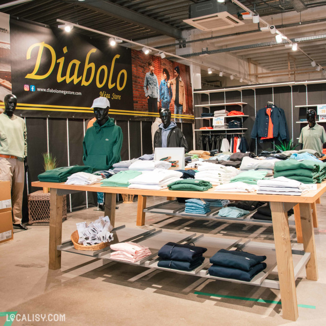 Rayon homme avec polos, sweats et vestes de marque exposés sur des tables et portants.