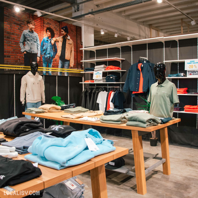 Rayon homme avec sweats, polos et vestes de marque exposés sur tables en bois.