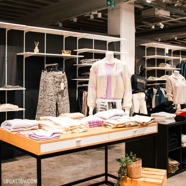 Rayon femme avec cardigans, pantalons imprimés et tops présentés sur des mannequins et étagères.