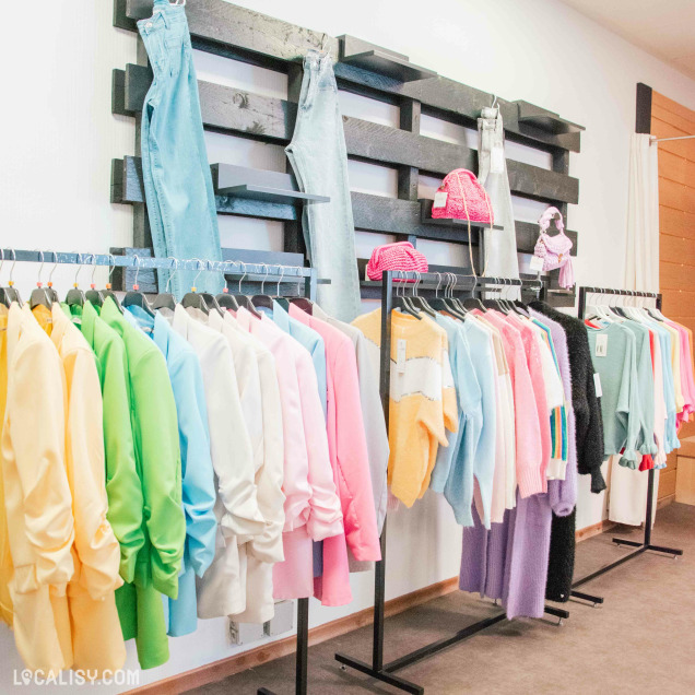 Magasin de vêtements Other Side à Amay avec une sélection pastel de vestes et pulls colorés.