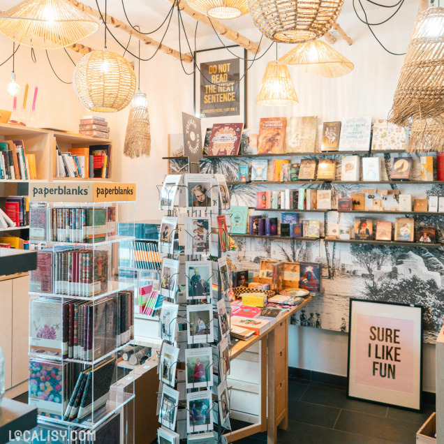 Intérieur de la librairie Livre'S à Marche-en-Famenne avec une sélection de livres et de décorations suspendues.