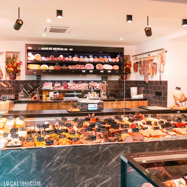 Présentoir de la boucherie Debruge - Halle de l'Artisan à Chênée offrant un assortiment de fromages, charcuteries et plats préparés.