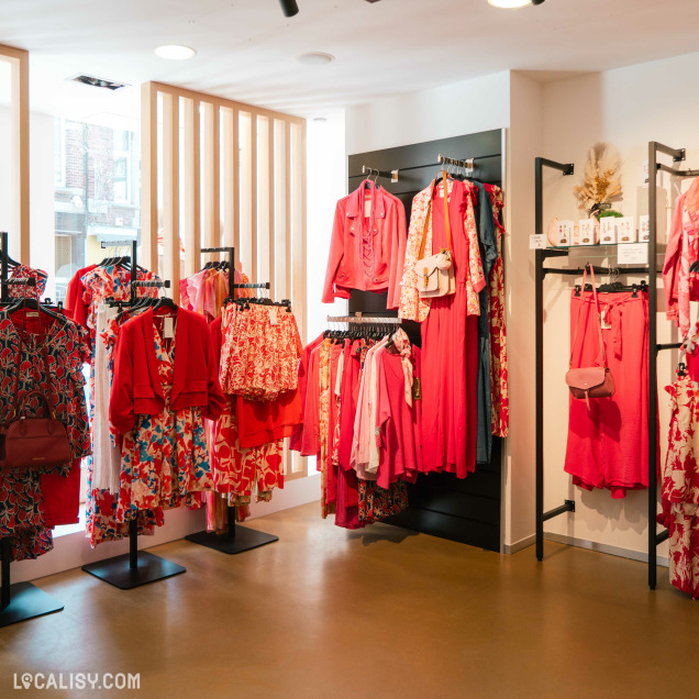 Intérieur du magasin de prêt-à-porter Les Audacieuses à Visé, avec une sélection de tenues élégantes.