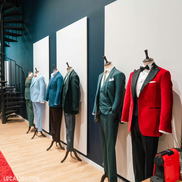 Rangée de mannequins en costumes colorés dans le magasin de costumes sur mesure Jaggs à Liège.