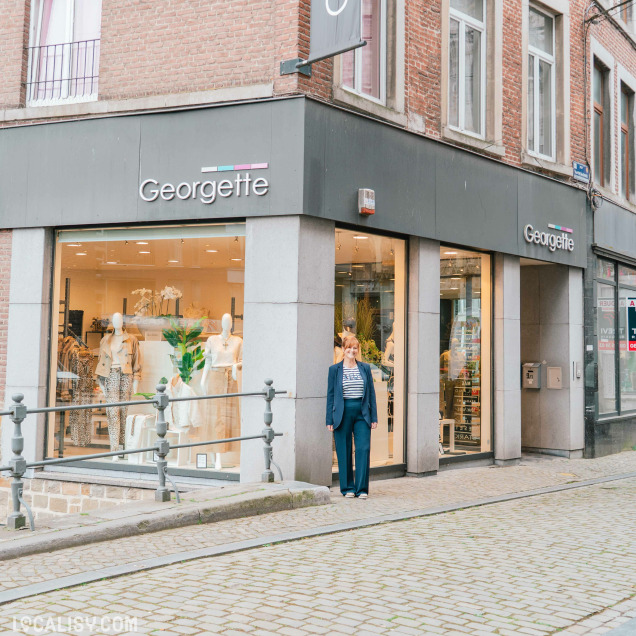 Façade de la Boutique Georgette à Huy avec une femme posant devant l'entrée.