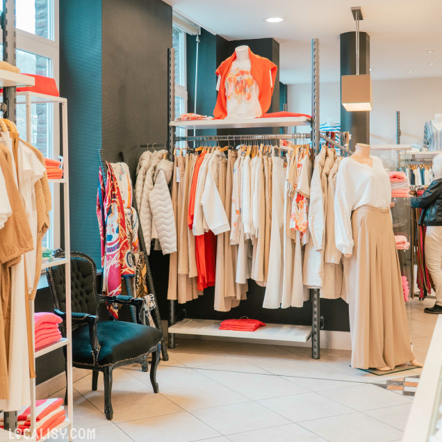 Vue de l'intérieur de la Boutique Georgette à Huy avec des mannequins et des portants de vêtements.