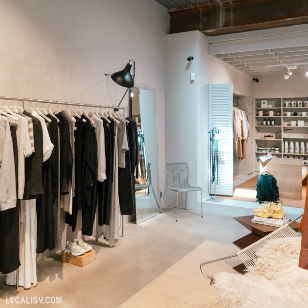 Aperçu de l'intérieur du magasin de vêtements Ginette à Liège avec des vêtements sur des cintres et un miroir.
