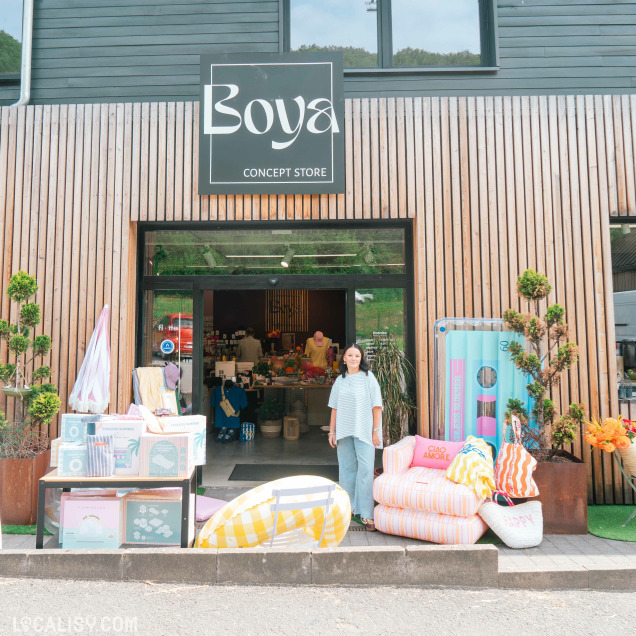 Façade du magasin Boya Concept Store à Theux avec une personne posant devant l'entrée et des articles extérieurs.