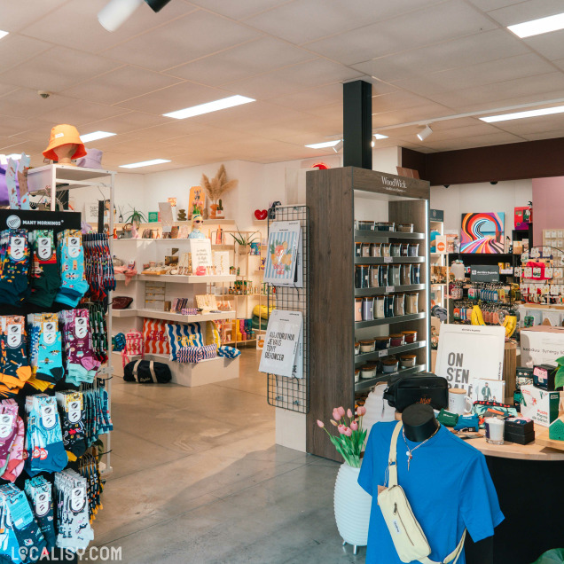 Vue large de l'intérieur du magasin Boya Concept Store à Theux avec des chaussettes, des bougies et d'autres articles.