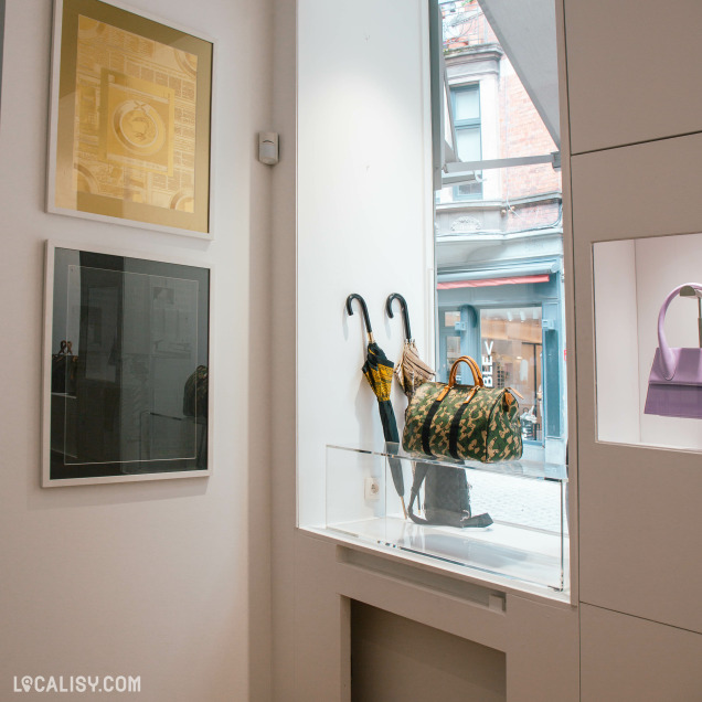 Vitrine du magasin de dépôt-vente Vingt-Trois Shop à Liège présentant des sacs et des parapluies.