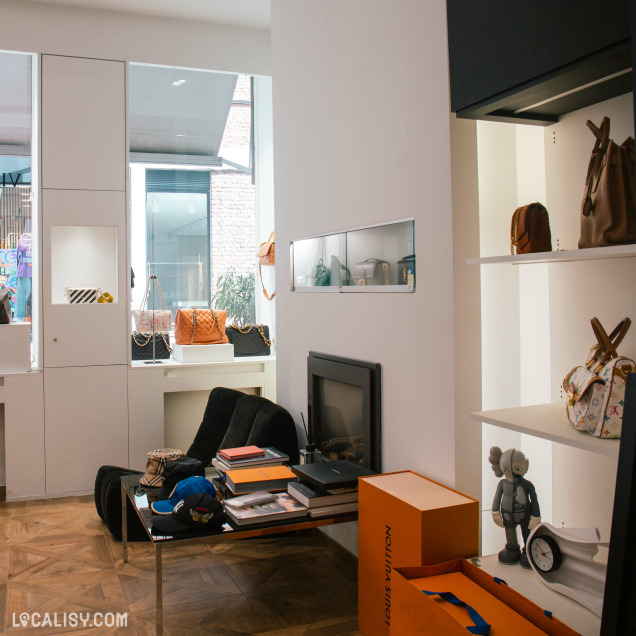 Espace intérieur du magasin de dépôt-vente Vingt-Trois Shop à Liège avec cheminée et accessoires de mode.