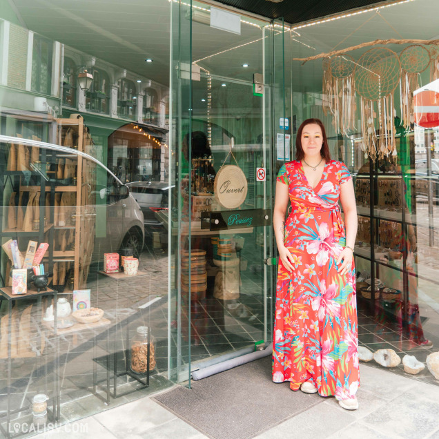 Façade de l'herboristerie La Boutique de l'Enchanteresse à Huy, avec une femme posant devant l'entrée.