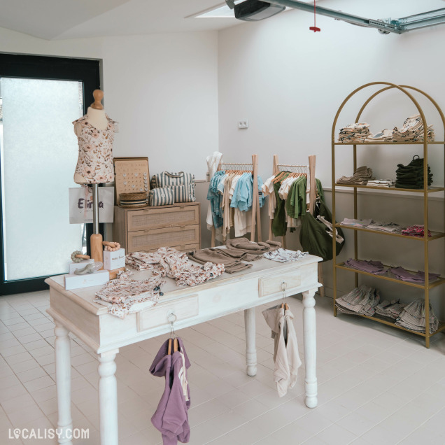 Ambiance intérieure du magasin de vêtements pour enfants Elima Eliott + Maman à Jupille, avec des présentoirs et des tables.