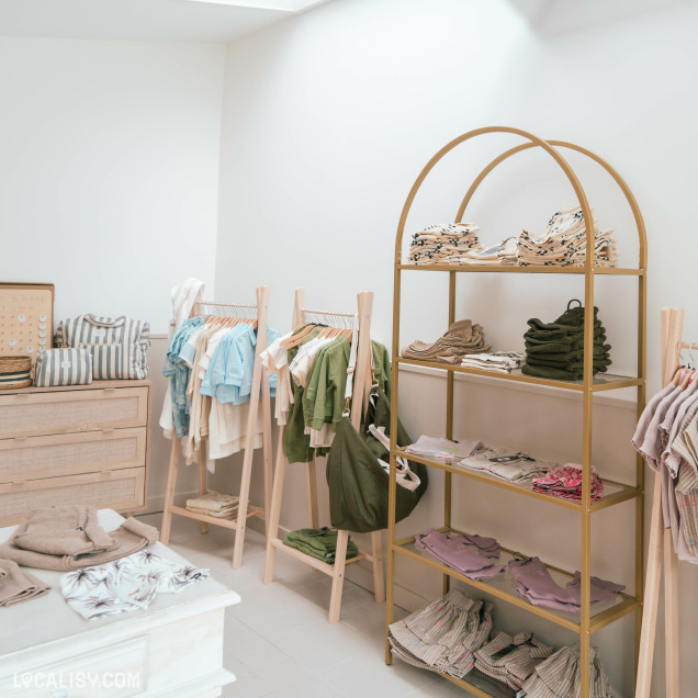 Intérieur du magasin de vêtements pour enfants Elima Eliott + Maman à Jupille, présentant des vêtements et accessoires pour bébés.