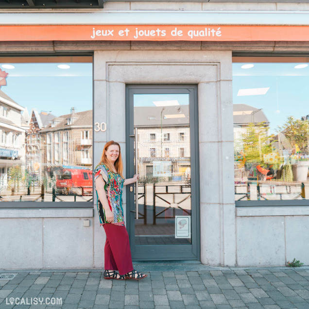Façade du magasin de jouets La poule aux jeux d'or à Rochefort avec une femme souriante devant la porte.
