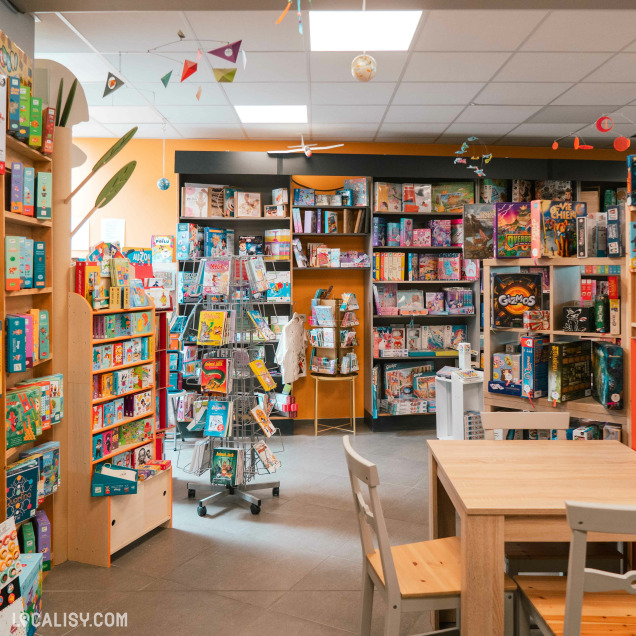 Zone du magasin de jouets La poule aux jeux d'or à Rochefort avec des jeux de société et une table d'activités.