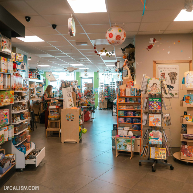 Intérieur du magasin de jouets La poule aux jeux d'or à Rochefort, présentant des poupées et des jeux de société.