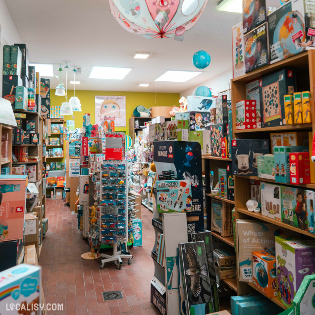 Intérieur du magasin de jouets Le Pont des Arts à Huy, montrant un rayon de jeux et une porte verte.