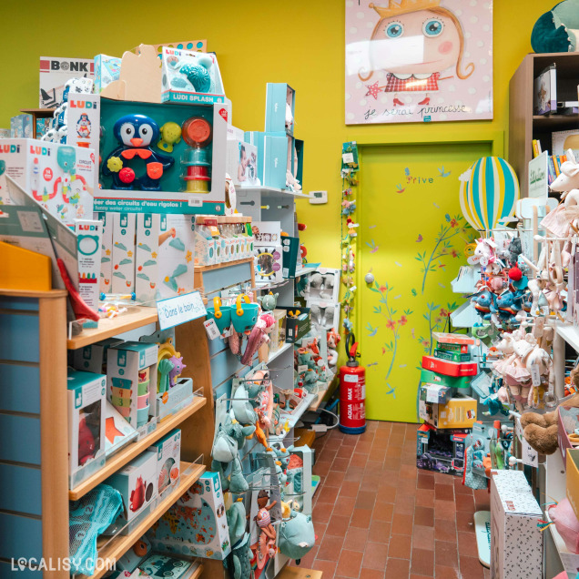 Vue générale de l'intérieur du magasin de jouets Le Pont des Arts à Huy, avec des étagères remplies de jeux et d'activités.