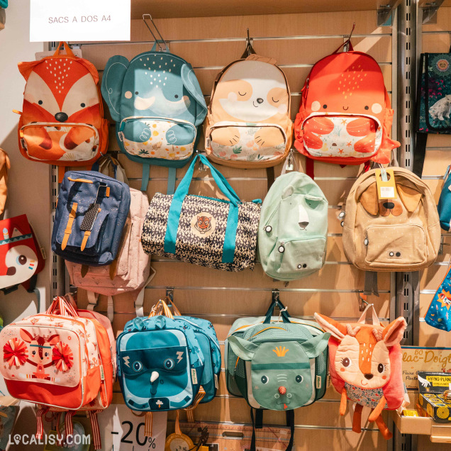 Allée centrale du magasin de jouets La poule aux jeux d'or à Rochefort avec des étagères remplies de jeux.