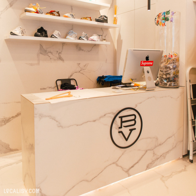 Comptoir de caisse avec le logo "BV Store" et des étagères de chaussures dans le magasin de streetwear à Liège.