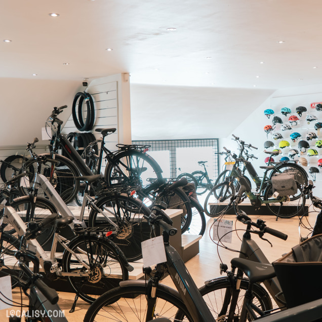 Intérieur du magasin E-bike à Nandrin, présentant une large sélection de vélos électriques et de casques.