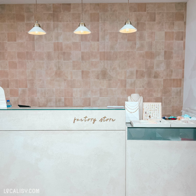 Comptoir de caisse de la boutique Factory Store à Huy, avec des bijoux présentés à côté.