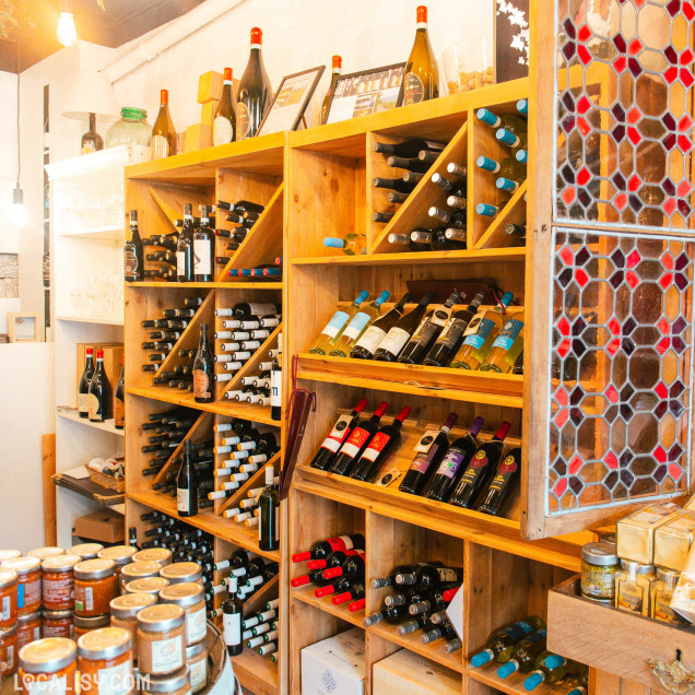 Un comptoir en bois clair et des étagères bien garnies créent une ambiance accueillante et authentique dans la boutique Storiedivino.