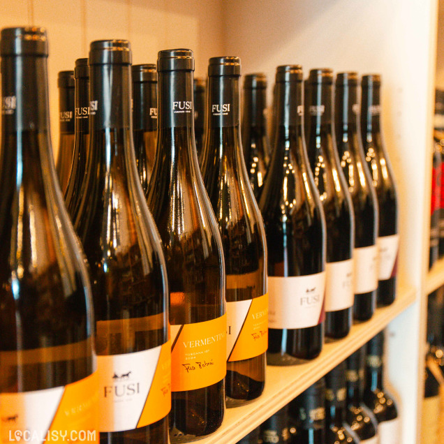 Une étagère murale en bois soigneusement organisée présente une sélection élégante de bouteilles de vin, mettant en valeur l’identité raffinée de Storiedivino.