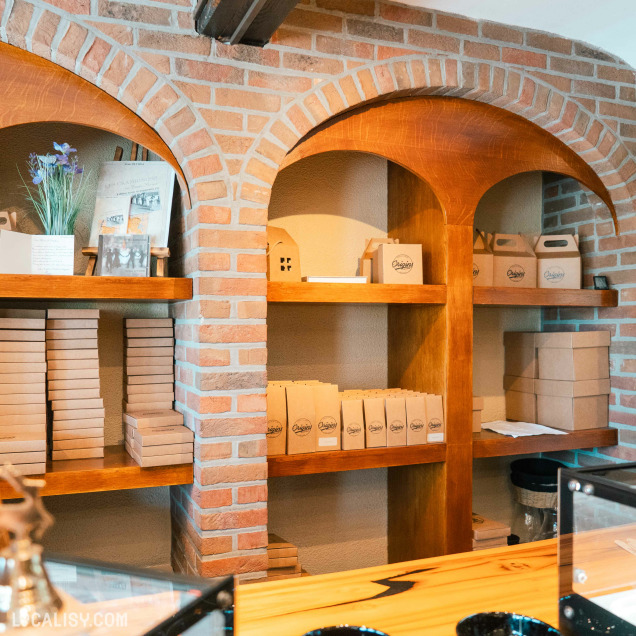 Des étagères en bois encastrées dans des murs en briques dévoilent les élégants emballages de la chocolaterie Origins, prêts à être offerts ou savourés.