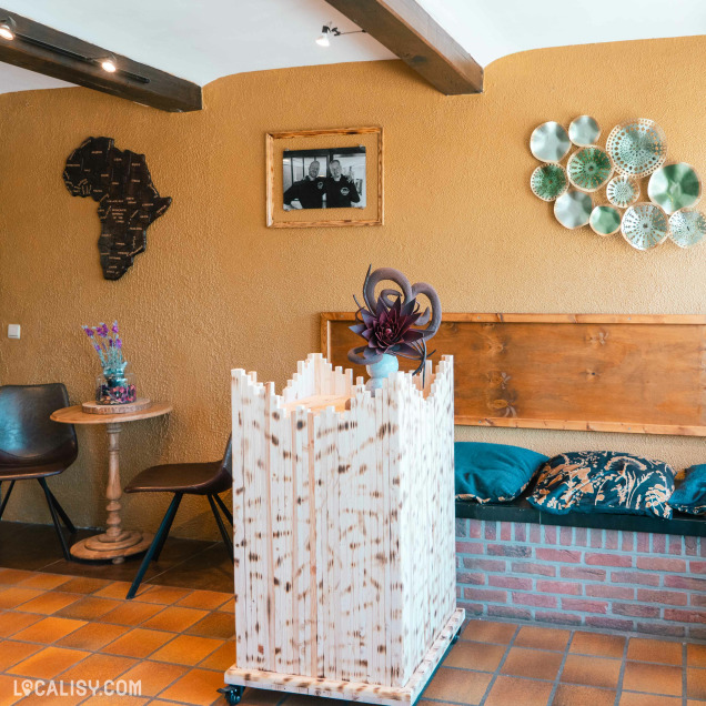Un coin chaleureux de la boutique mêle décoration africaine, banquette en briques, fleurs séchées et objets design pour une ambiance artisanale et conviviale.