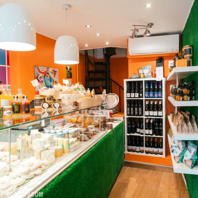Intérieur de la crèmerie Le bonheur est dans le pré à Huy, avec des meules de fromage sur des étagères et un comptoir de vente.