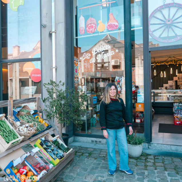 Façade de l'épicerie italienne Les délices de Maria à Huy, avec la gérante posant devant l'entrée.