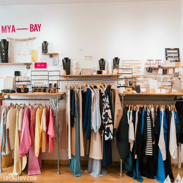 Vue des collections de vêtements et de bijoux Mya-Bay sur des portants et des étagères dans le magasin Native Boutique à Huy.