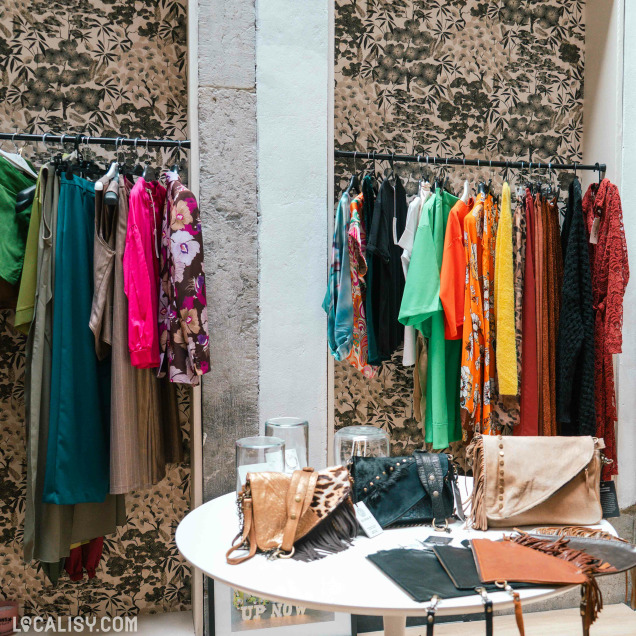 Portants de vêtements colorés et table d'accessoires dans la boutique de prêt-à-porter pour femmes Up now à Huy.