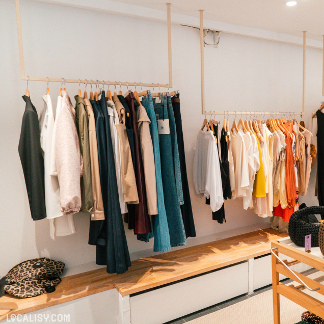Vêtements de mode pour femmes suspendus sur des cintres en bois dans le magasin Up now à Huy.
